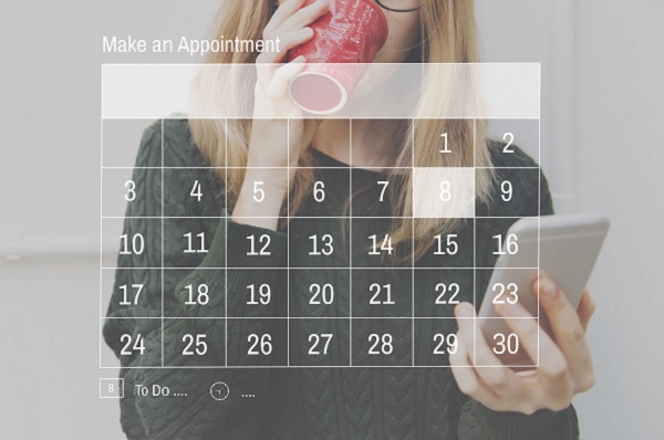 Woman looking at a calendar on a screen whilst drinking from a mug